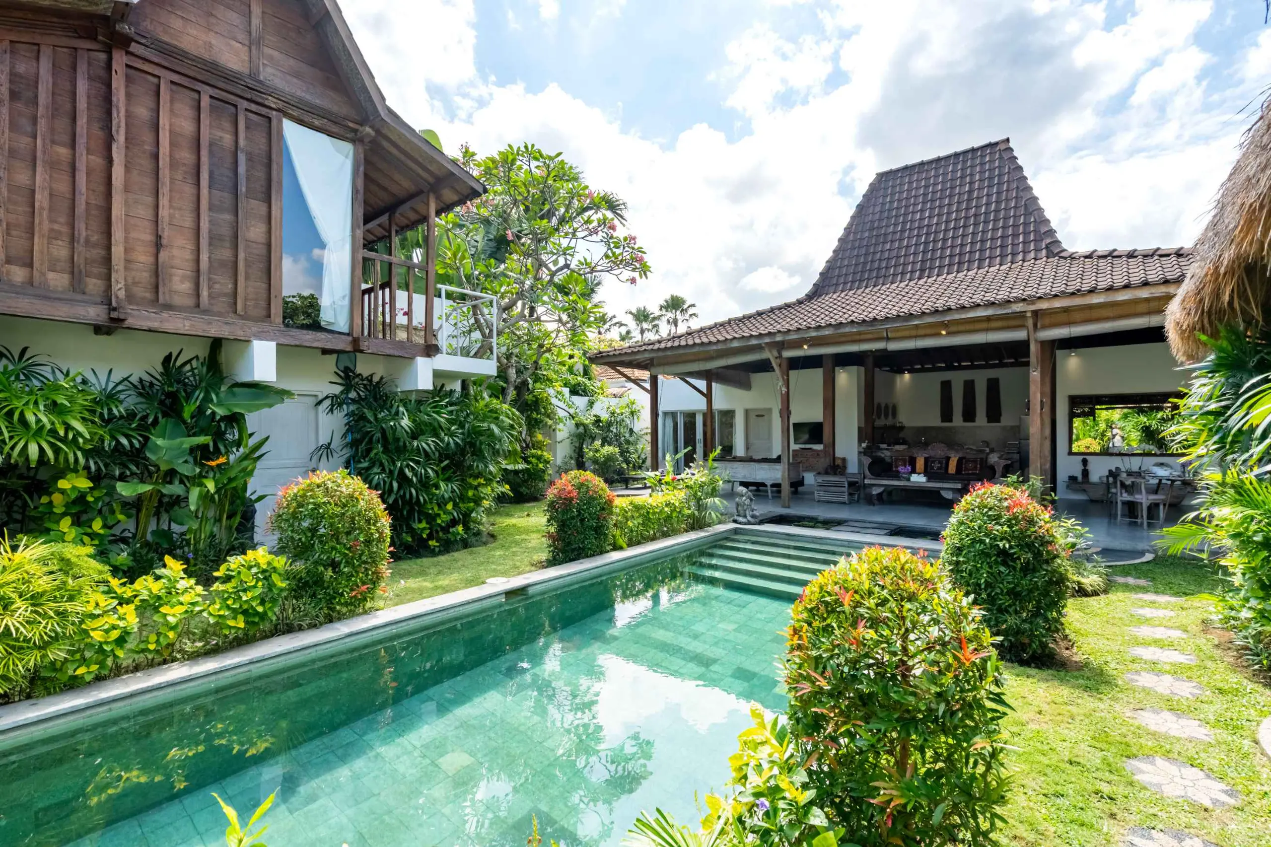 The long pool under palms and open sky — the quiet side of Seminyak