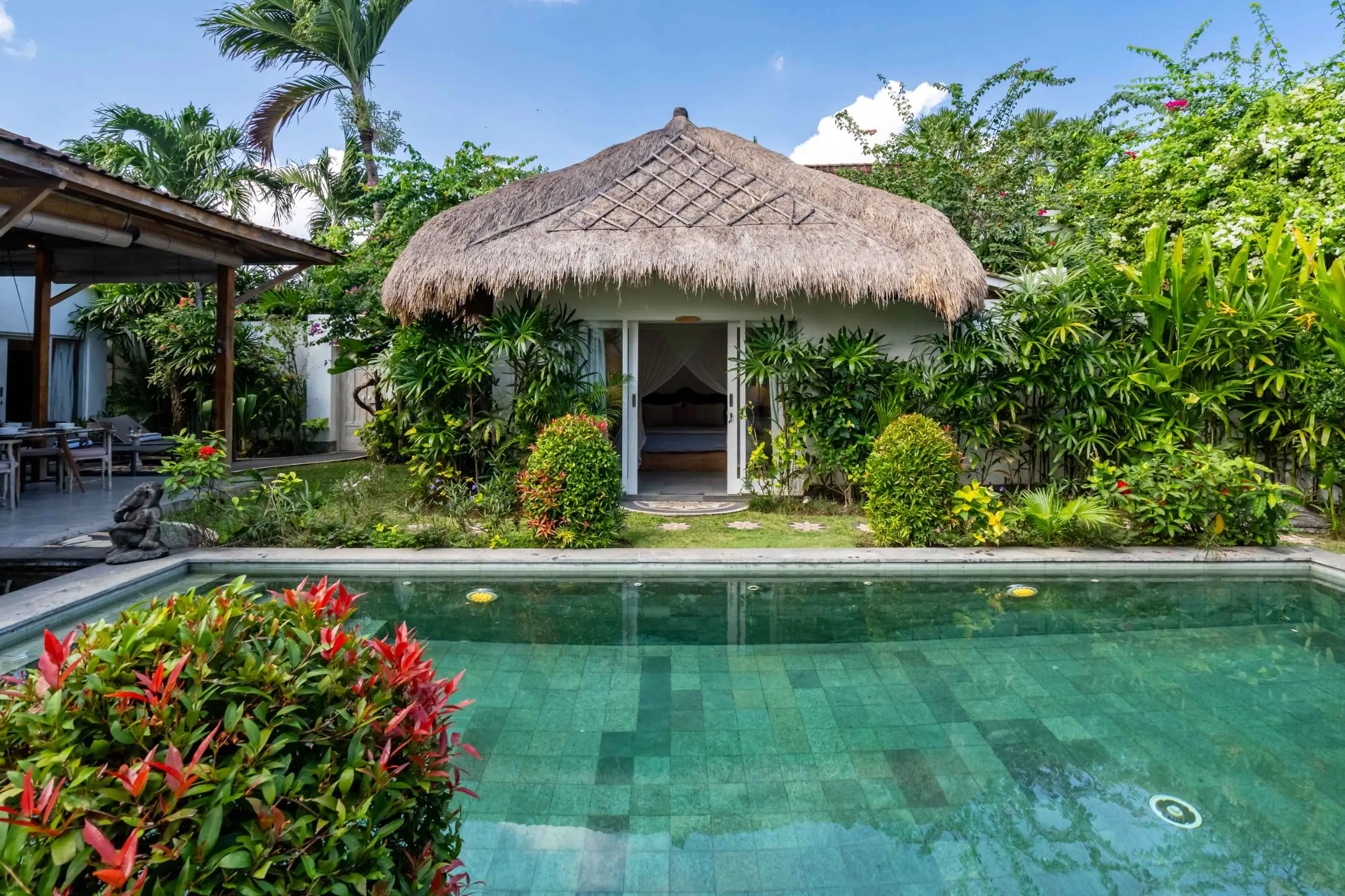The lane side of the villa — thatch, palms, whitewash