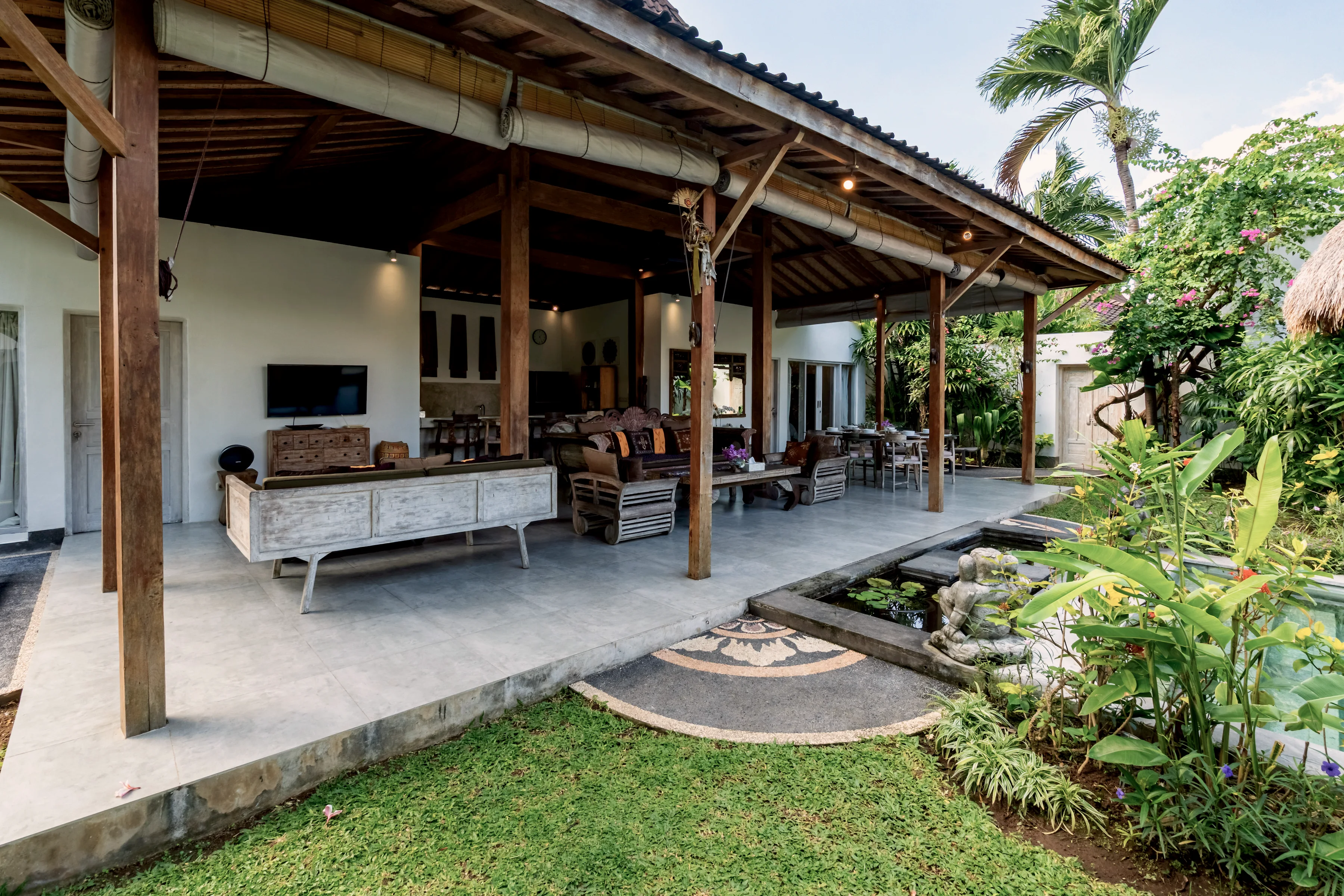 The covered terrace and its long sofa, opening onto the grass
