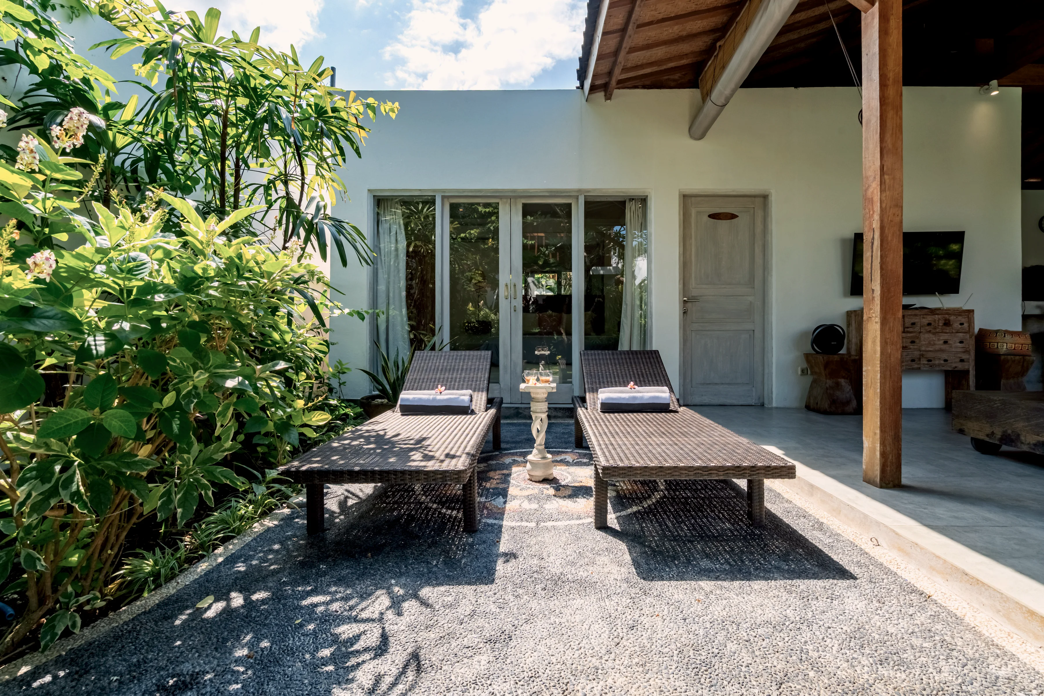 Two loungers on the terrace outside a bedroom’s glass doors