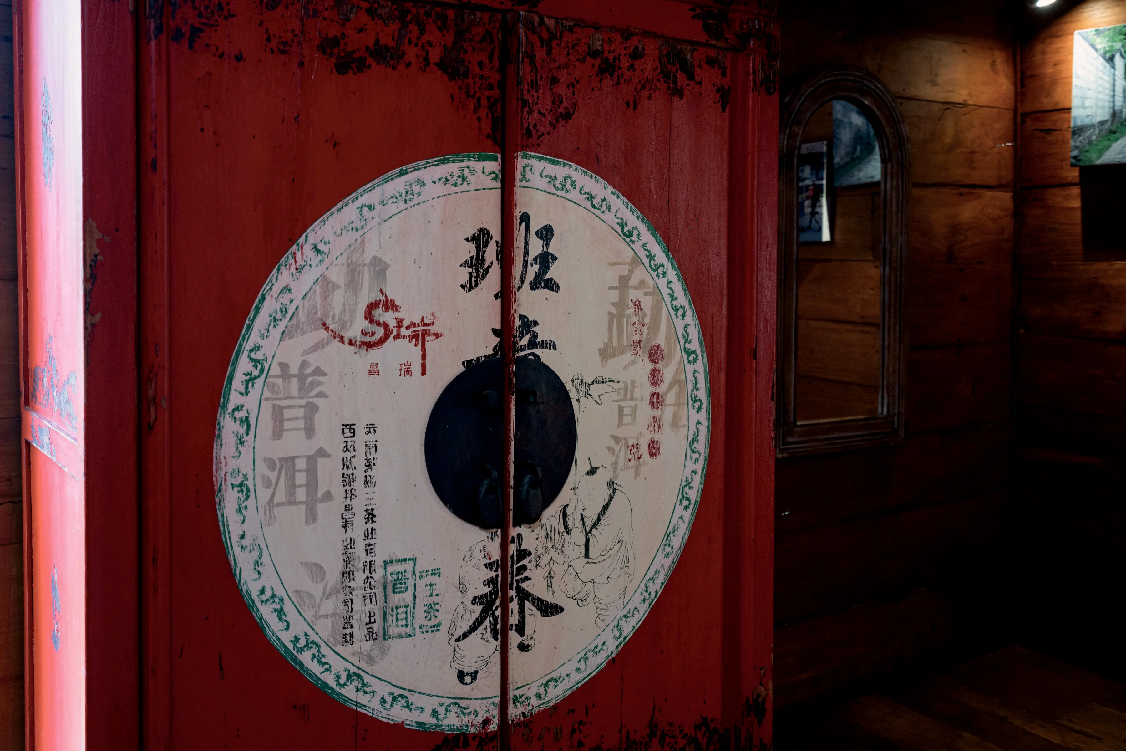 A red lacquered cabinet door with a painted roundel