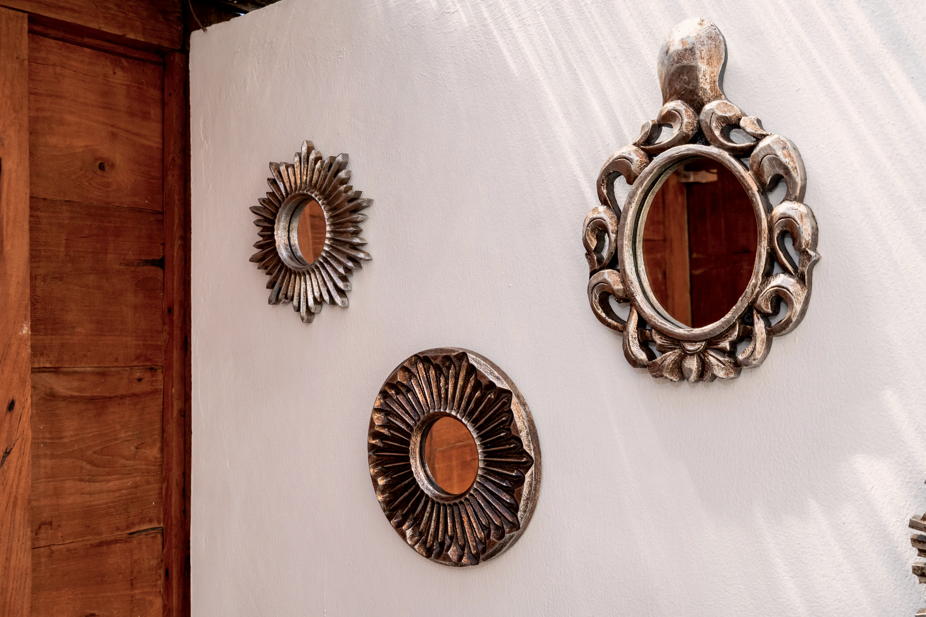 Carved wooden mirrors on a white wall
