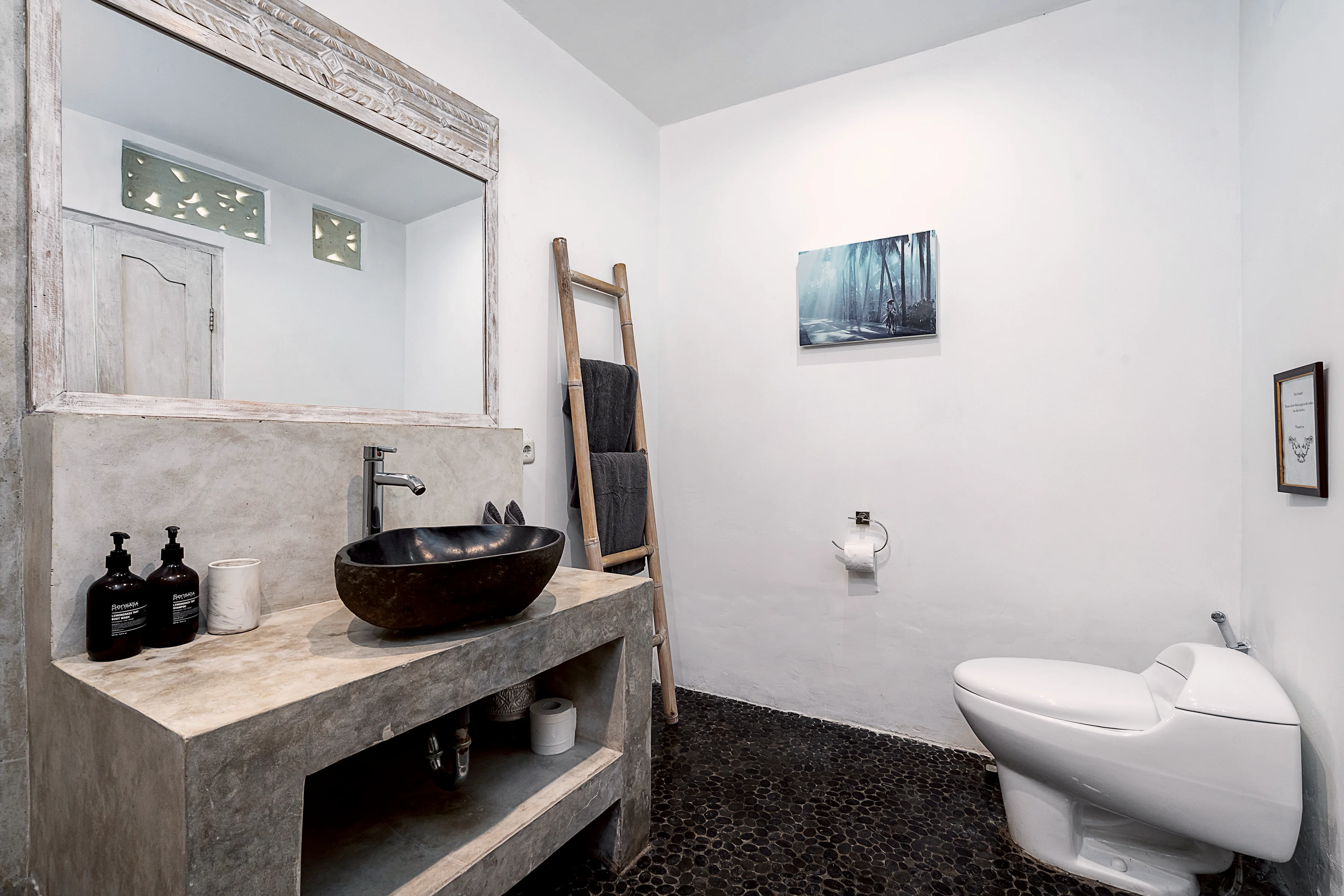 A bathroom with a mirror, a stone basin and a towel ladder