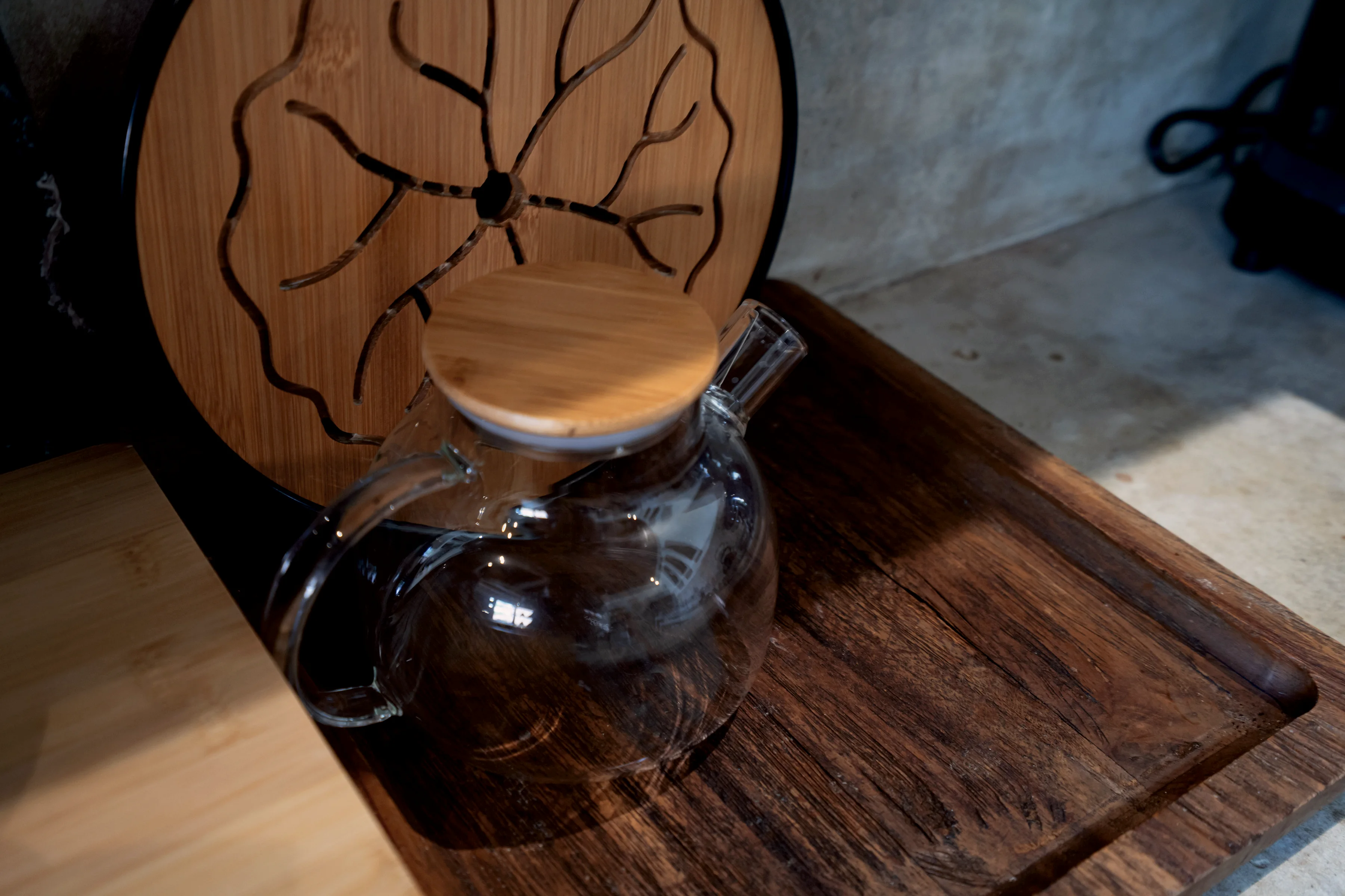 A glass teapot on a wooden tray in the kitchen
