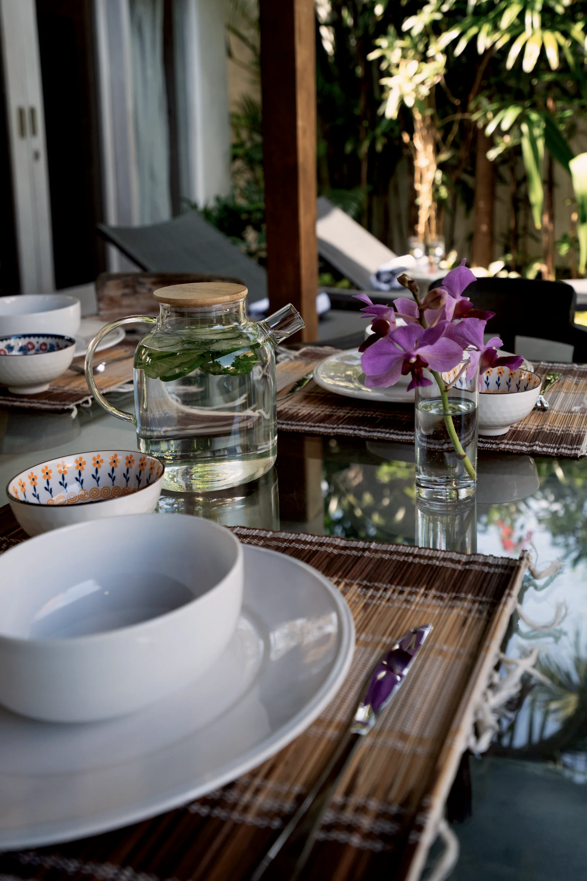 A glass teapot, bowls and a purple orchid on the table