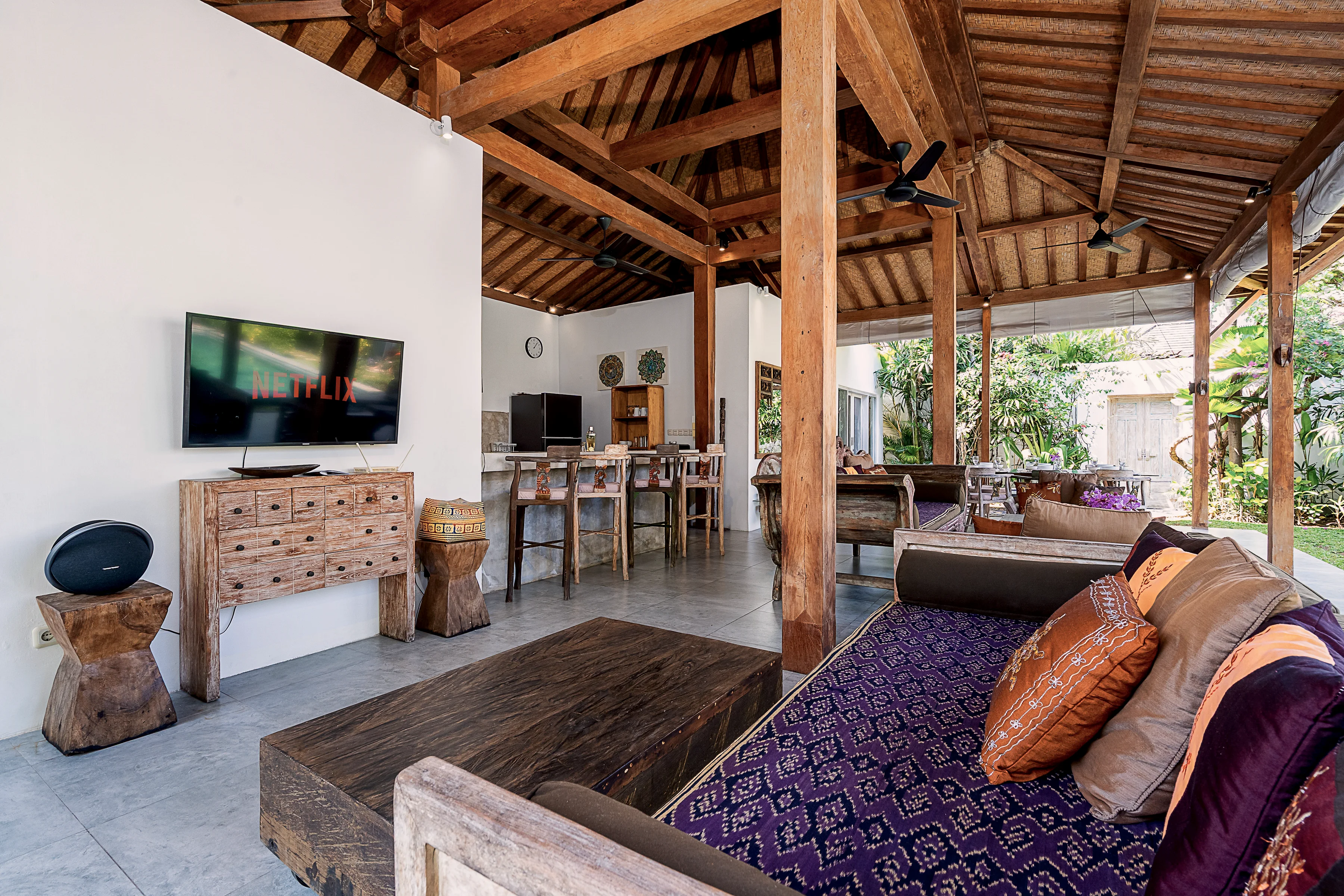 The lounge corner: a woven daybed, a carved chest and a television