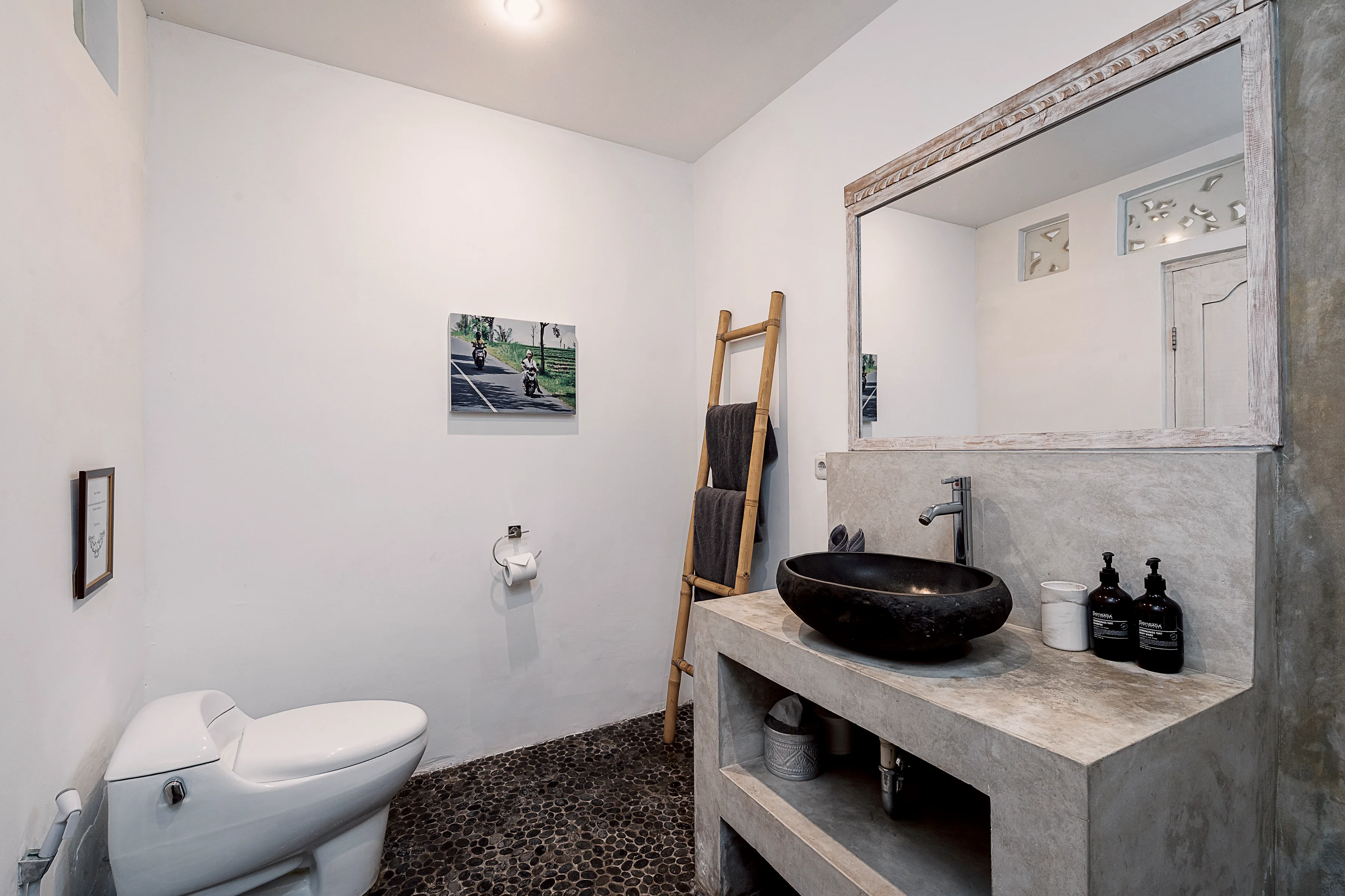 A bathroom with a stone basin, a towel ladder and a toilet