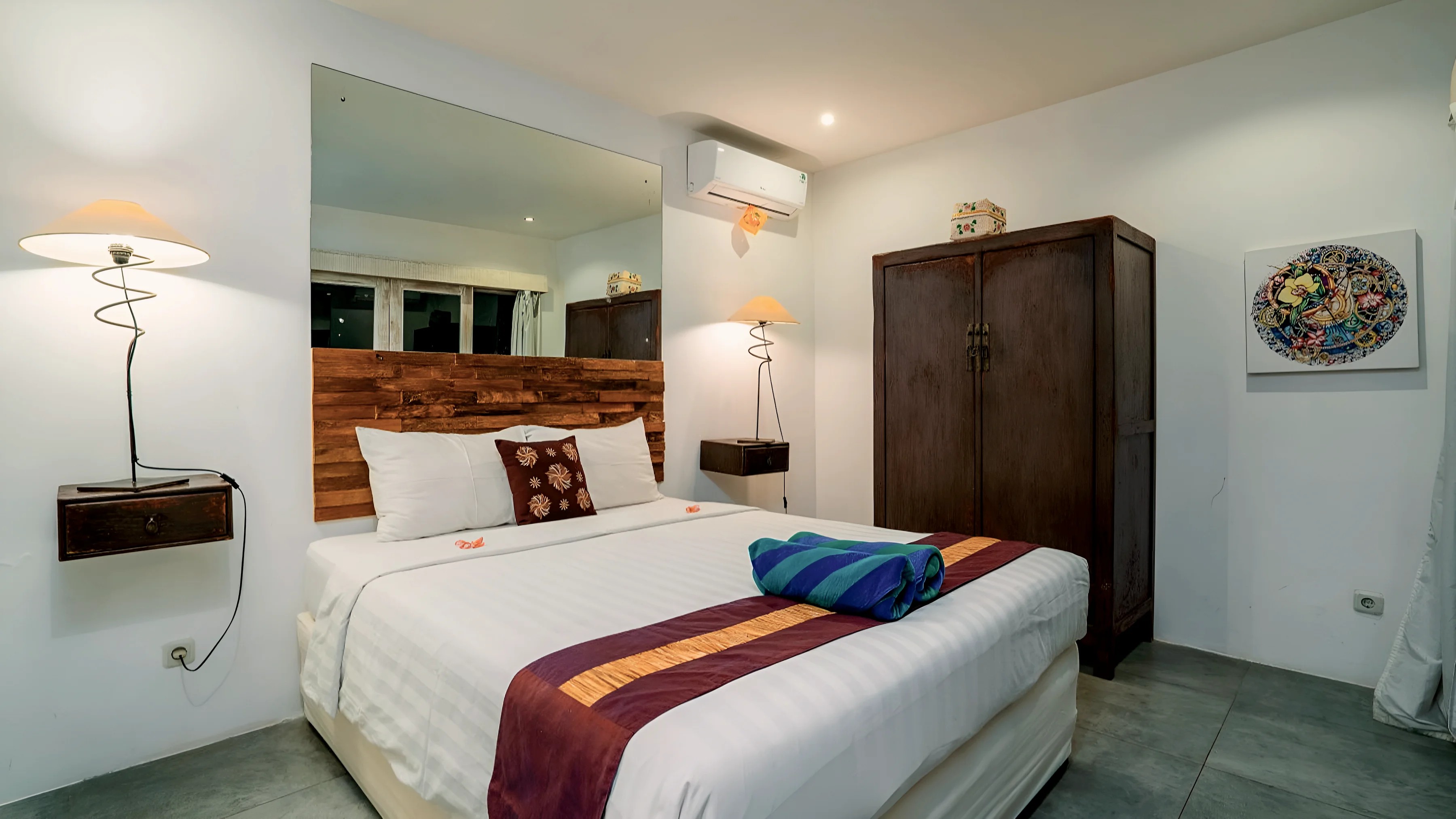 A white bedroom with a dark wardrobe and a painted plate on the wall