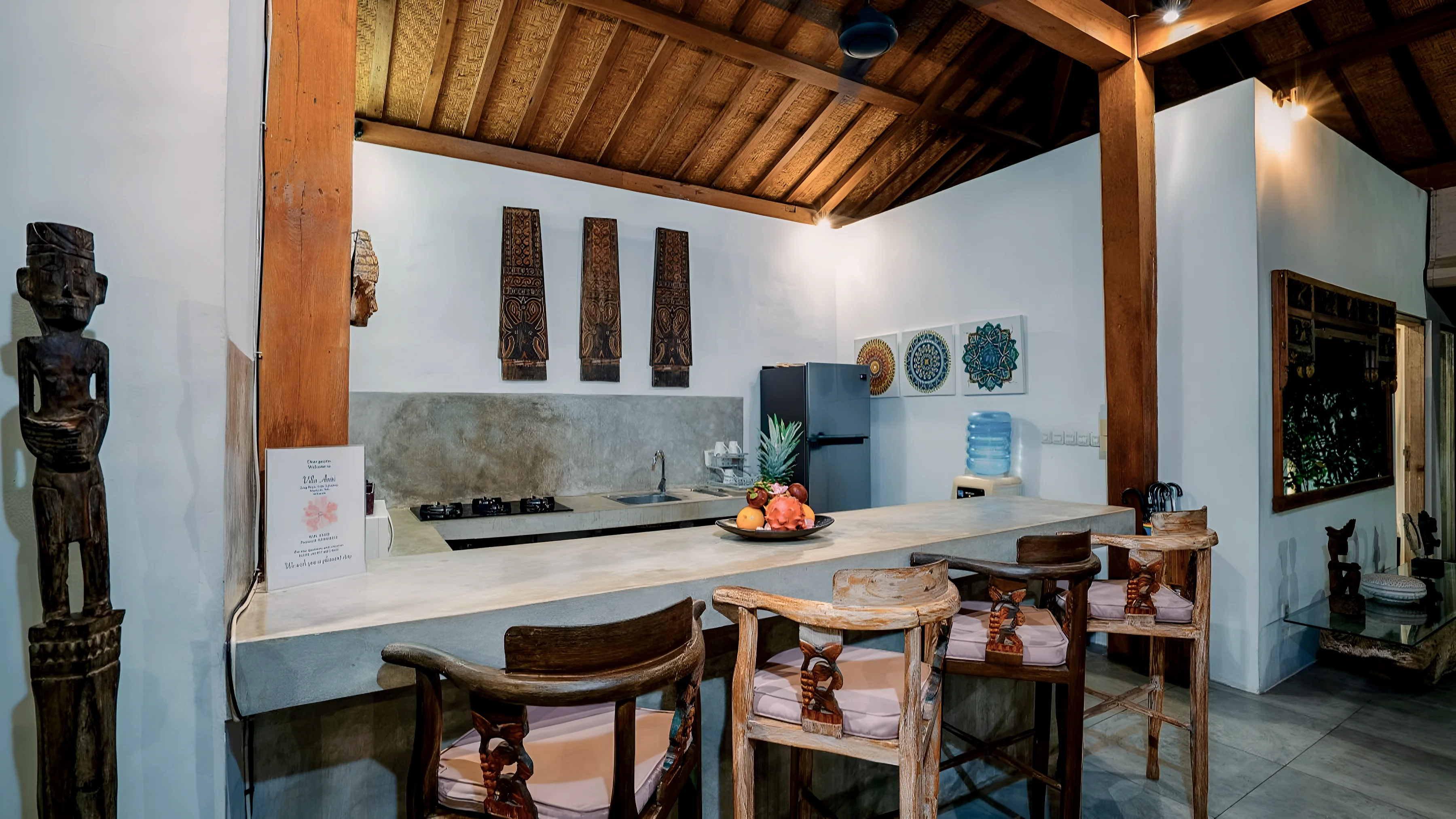The kitchen and bar from the side, a carved wooden figure by the counter